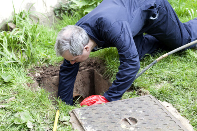 Man checking a drain blockage in a garden