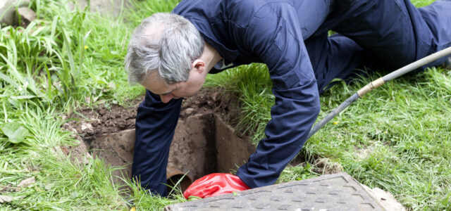 Man checking a drain blockage in a garden