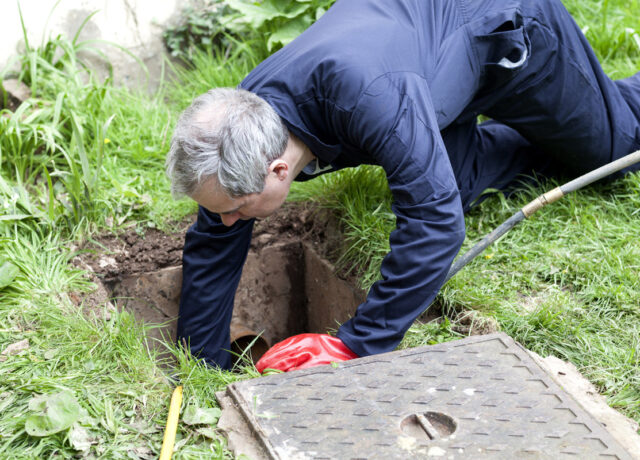 Man checking a drain blockage in a garden